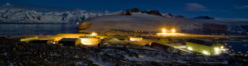 A research base lit up in an icy landscape in the dark