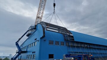 A large crane on the back of a large blue building