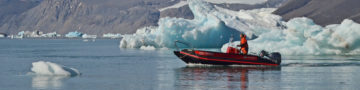 A small boat in a body of water with a mountain in the background.