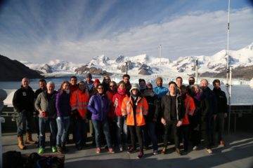 A group of people standing in front of a crowd posing for the camera.