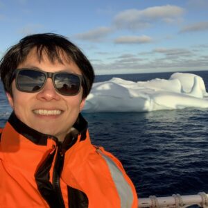 A man wearing sunglasses and standing next to a body of water
