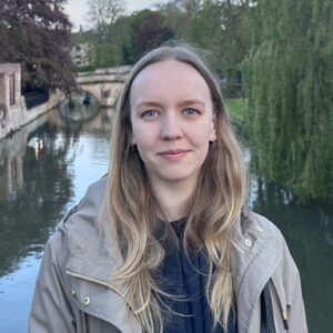 A person smiling next to a body of water