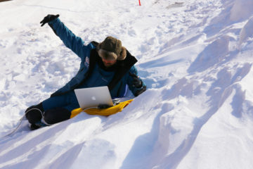 A person lying on top of a snow covered slope.