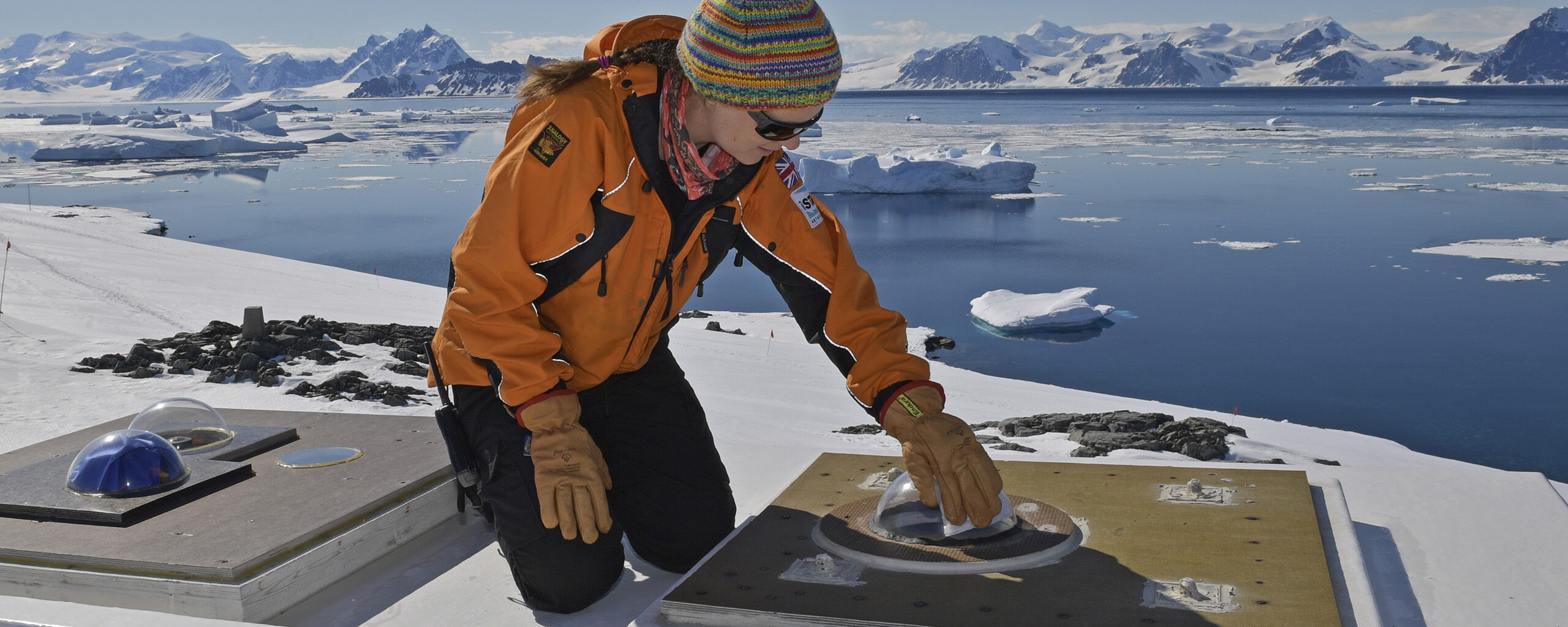 A scientist maintaining an optical instrument on an ice shelf.