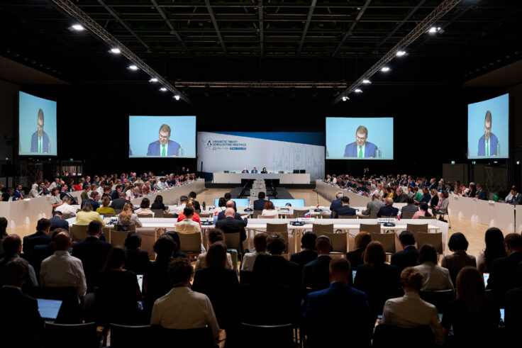 A group of people in front of a crowd of people watching a screen
