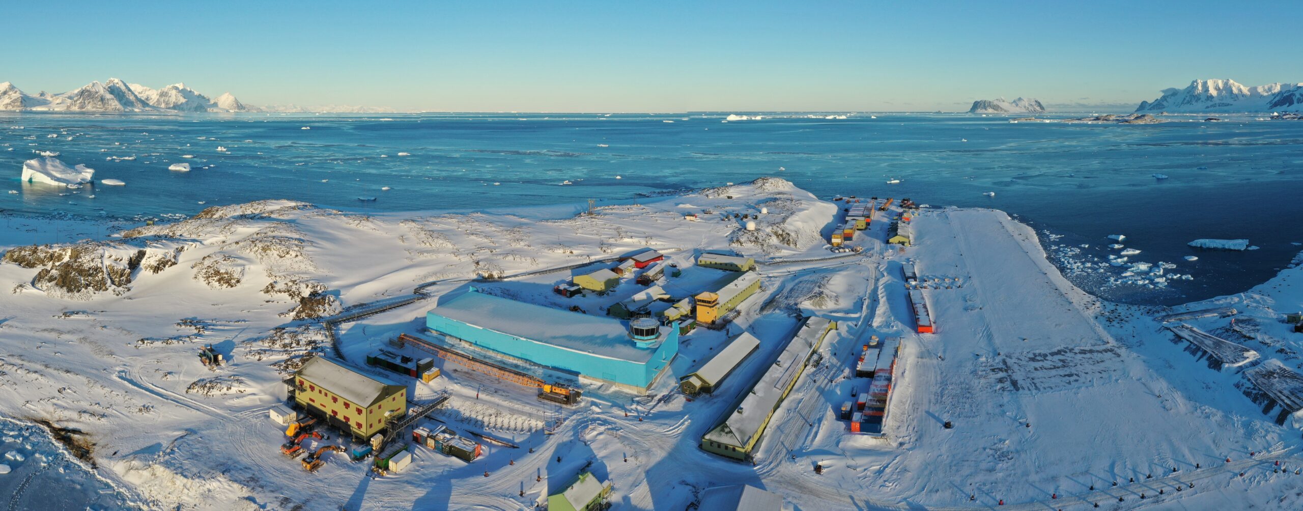 A panoramic view of Rothera Research Station. The bright blue Discovery building is prominent in the foreground with views into the Southern Ocean