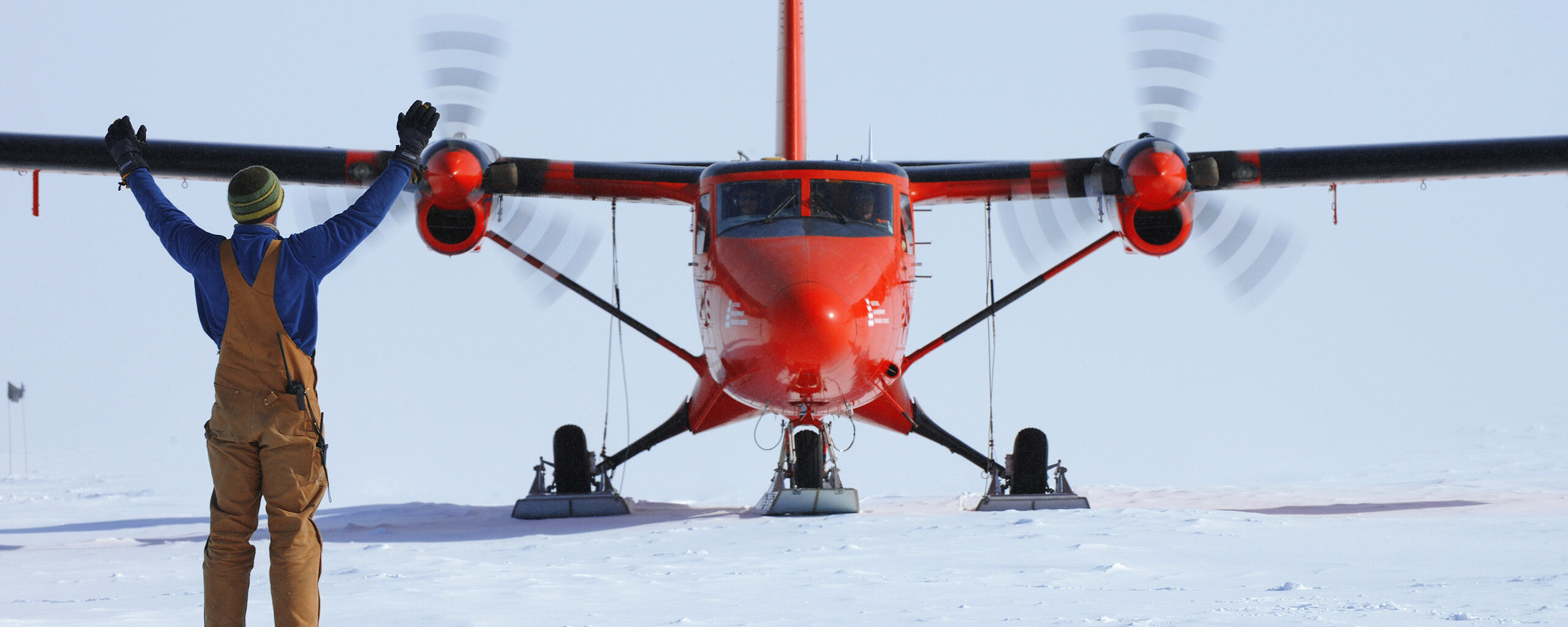 A red twin otter plane landing on skis