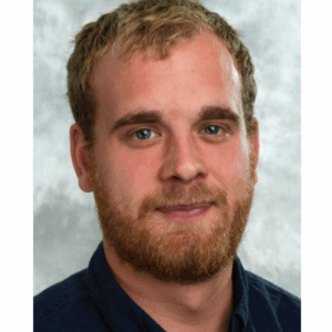 A man wearing glasses and smiling at the camera